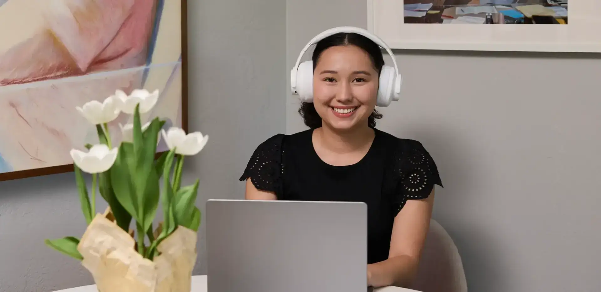 Student wearing a white pair of headphones while working with her laptop